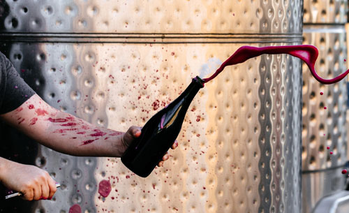 Winemaking hand disgorging a bottle of Sparkling Syrah. It is very messy!
